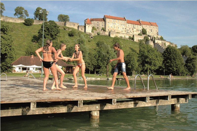 Junge Menschen auf einem Badesteg am Wöhrsee mit Burg im Hintergrund