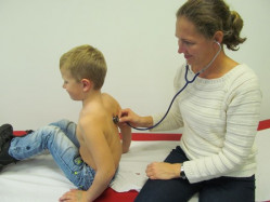 Ärztin hört Jungen bei schulärztlicher Untersuchung mit Stethoskop ab