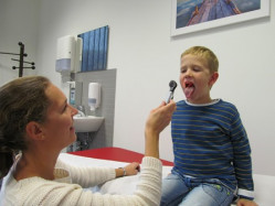Schulärztliche Untersuchung Ärztin leuchtet in Mund eines Jungen