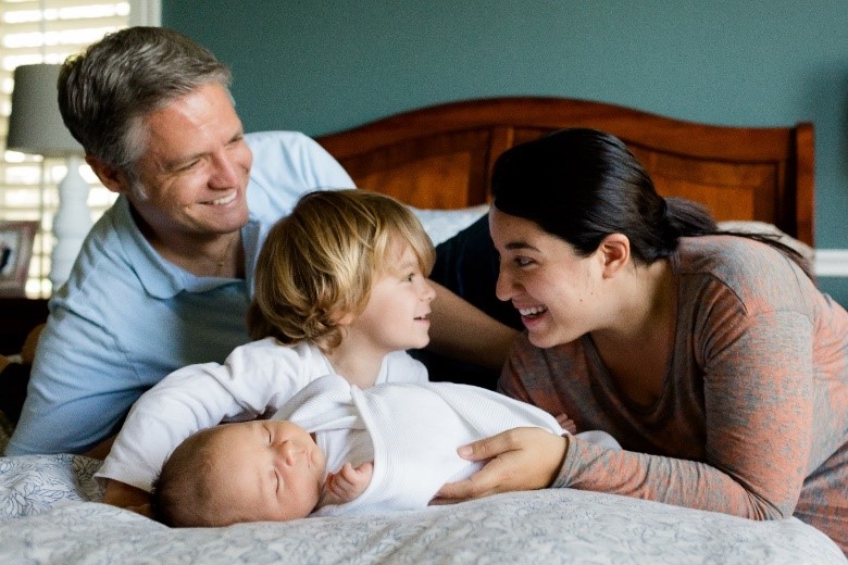 Auf dem Bett liegen die Eltern von zwei kleine Kinder