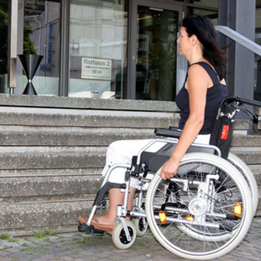Junge Frau mit Rollstuhl vor einer Treppe