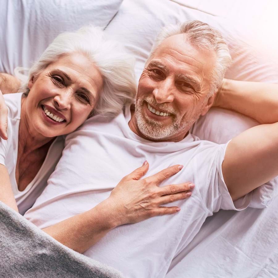 glückliche Senioren liegen im Bett