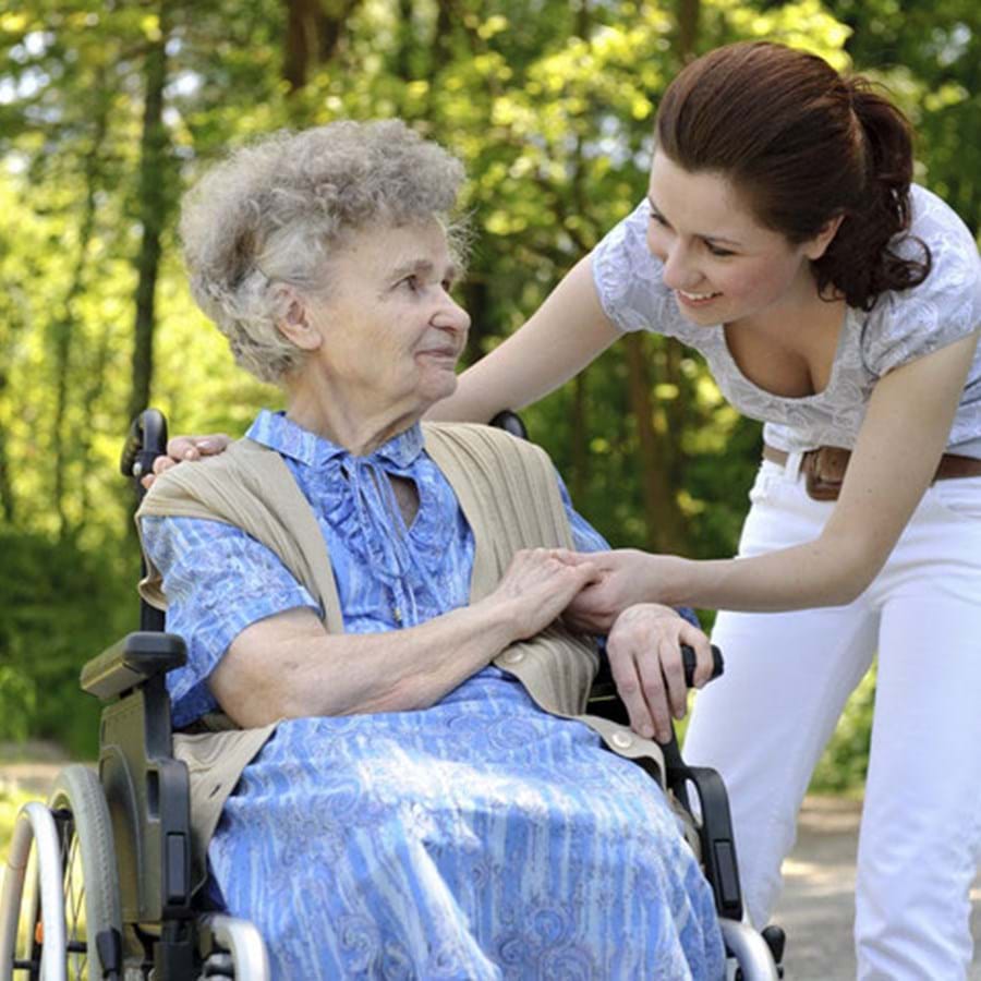 Junge Frau hilft einer Seniorin im Rollstuhl