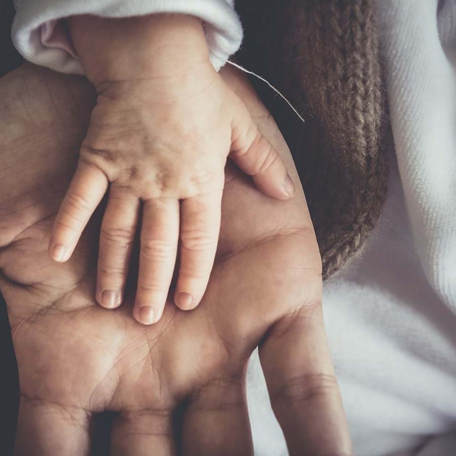 Die Hand eines Kleinkindes liegt auf der Hand eines Erwachsenen
