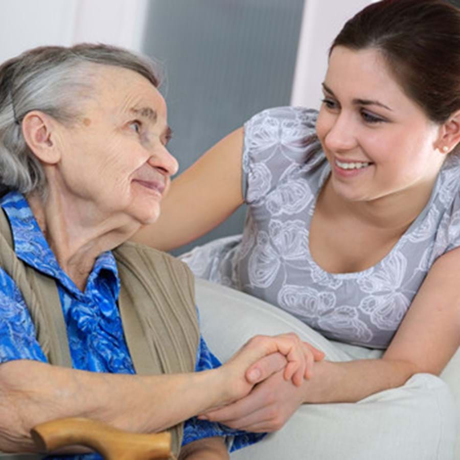 Eine Frau hält die Hand einer älteren Frau während sie sich anlächeln